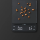 Chef Matteo elektronisk kaffevægt i sort med kaffebønner på vejepladen og digitalt LED-display, der viser en vægt på 2,4 gram.